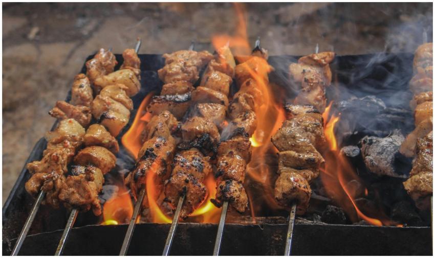 Juicy skewers of grilled meat sizzling over open f