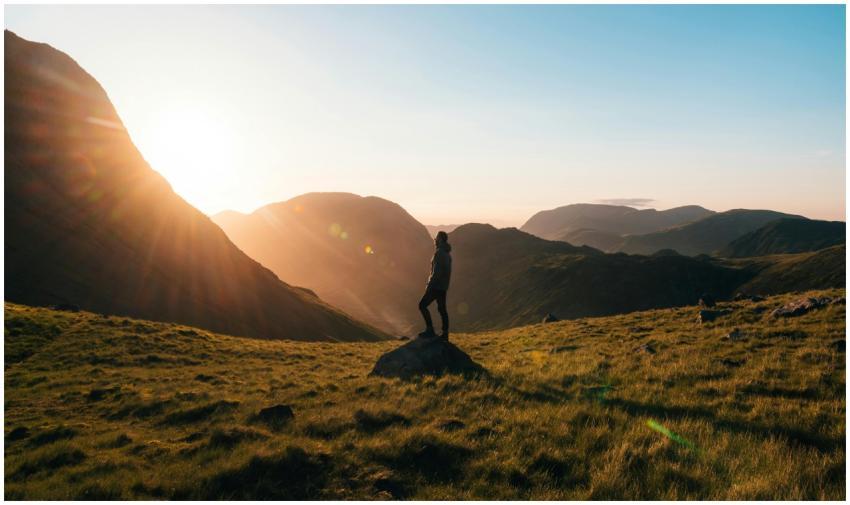 Silhouette of a person standing on a hill during s