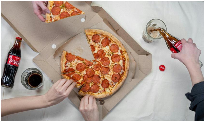 Top view of friends sharing pepperoni pizza and en