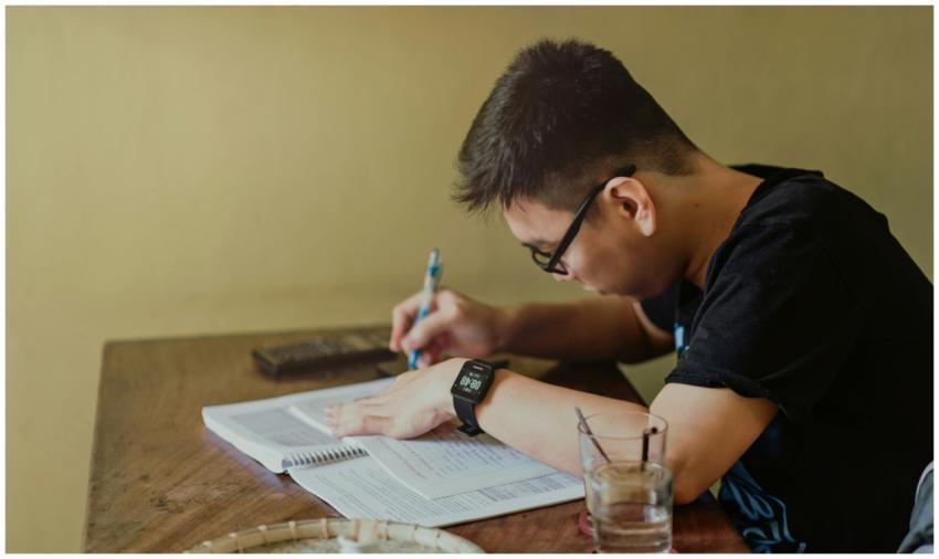 A young man concentrates on studying at his desk,