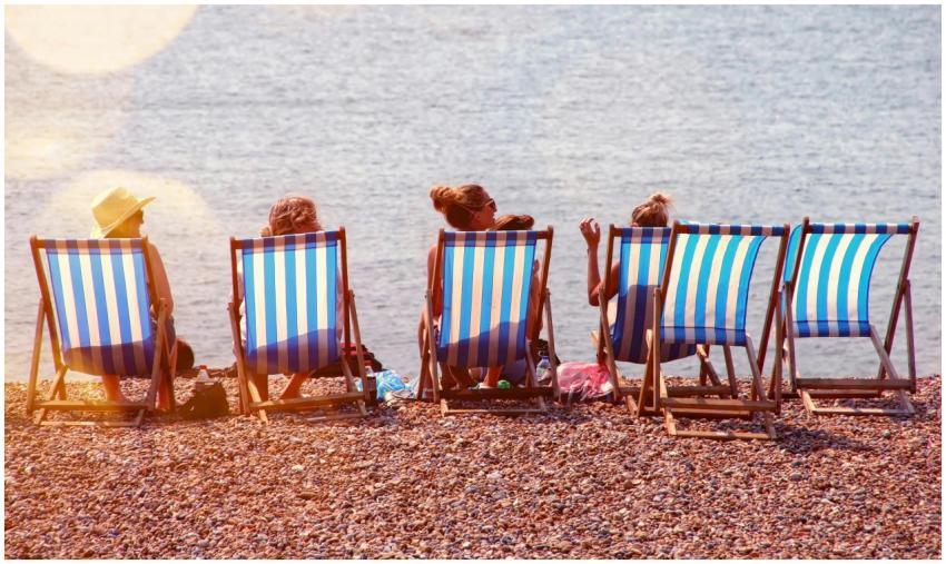 Five people relaxing on a pebble beach with stripe