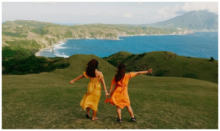 Two women in vibrant summer dresses enjoy the brea