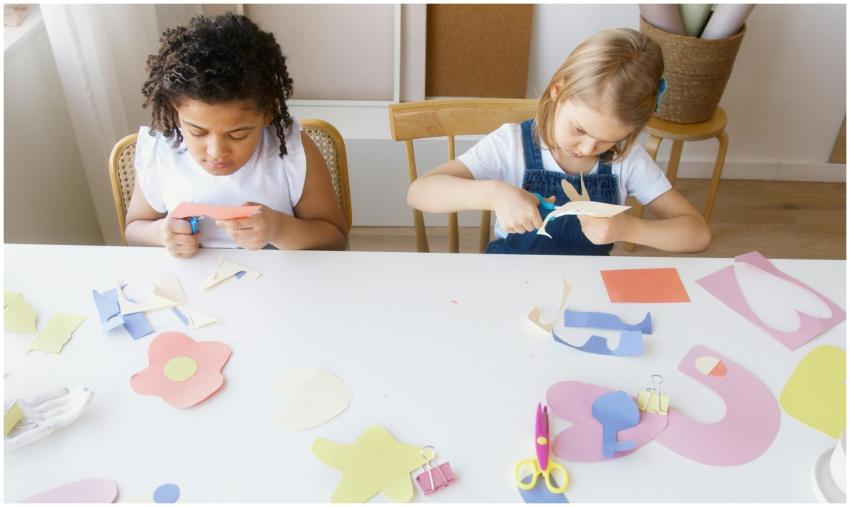 Two children crafting colorful paper shapes, focus