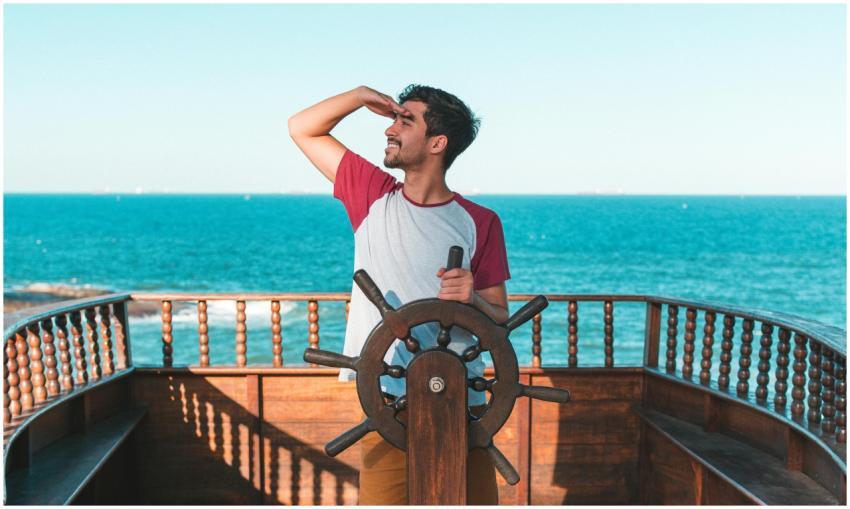 A young man enjoys steering a boat on a sunny summ