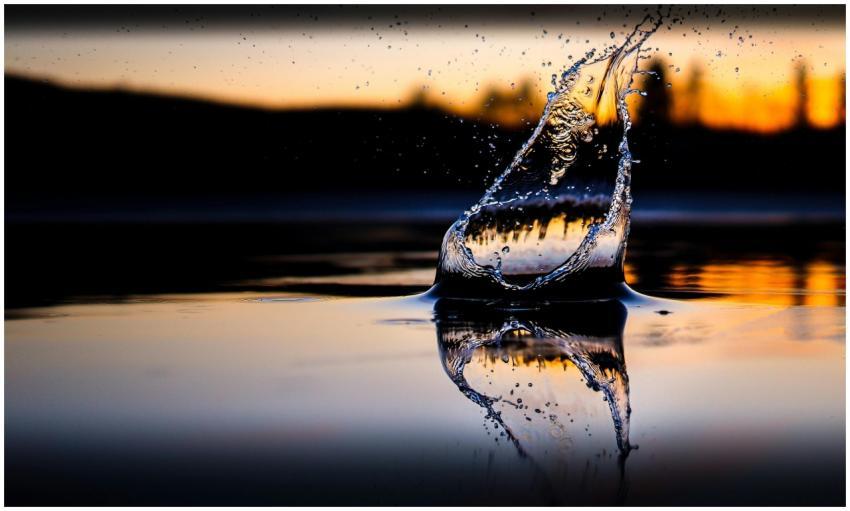Dramatic water splash with sunset reflection creat