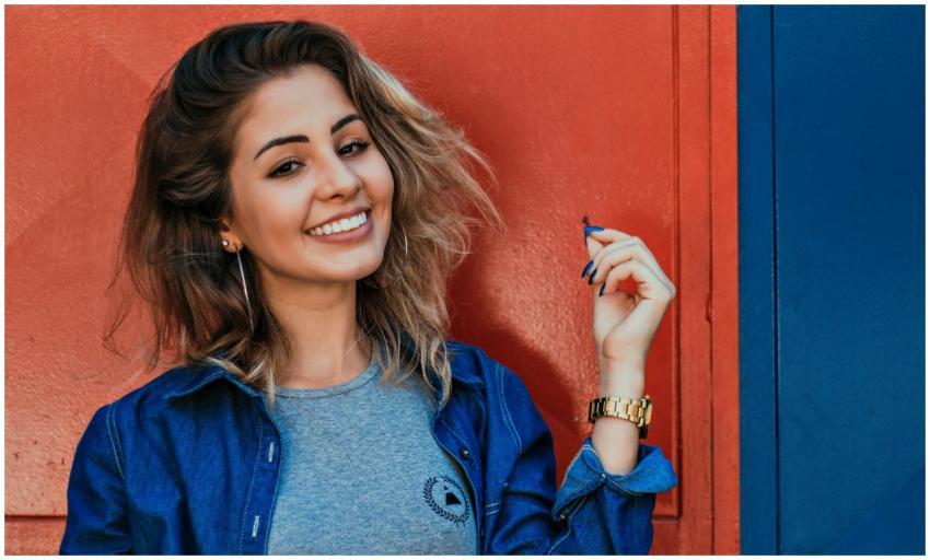 A woman in a denim jacket smiling brightly against