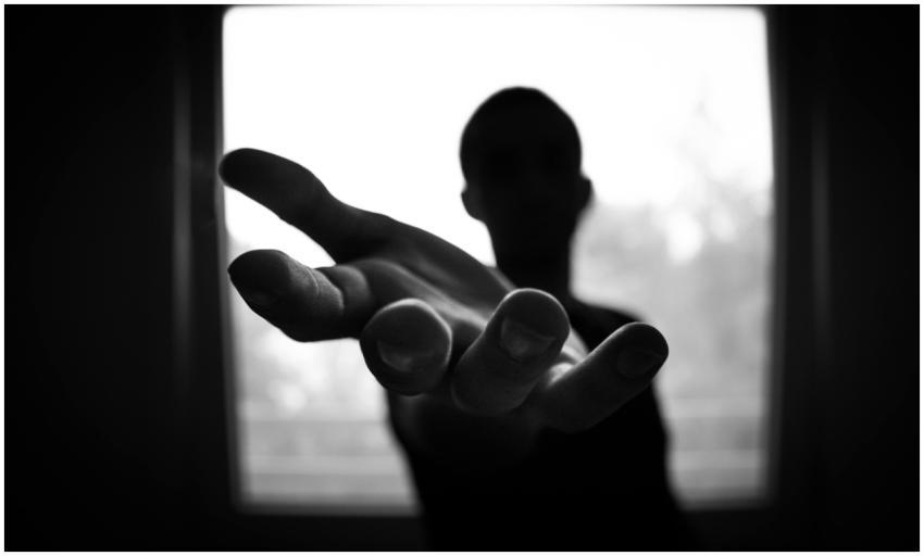 Silhouette of a hand reaching out in a black and w