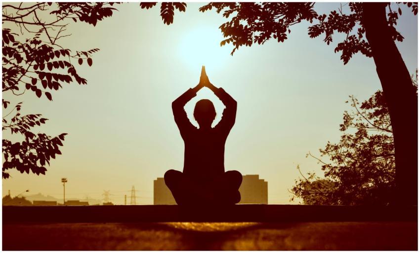 Silhouette of a person practicing yoga outdoors du