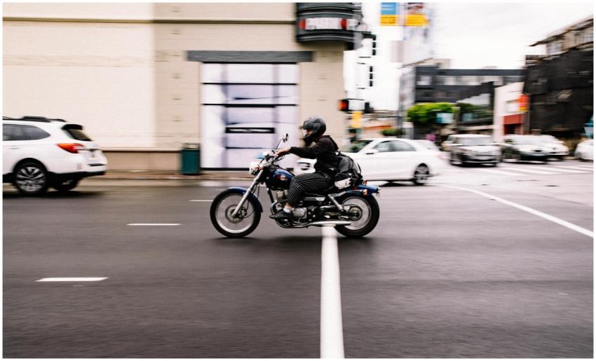 Motorcyclist speeds through a busy city street in