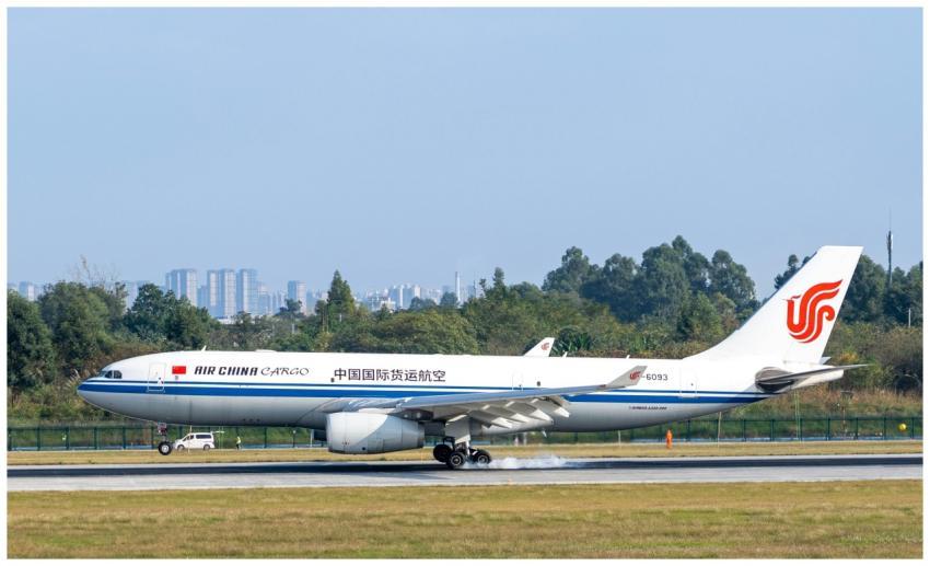 Air China Cargo plane landing on a runway with cit