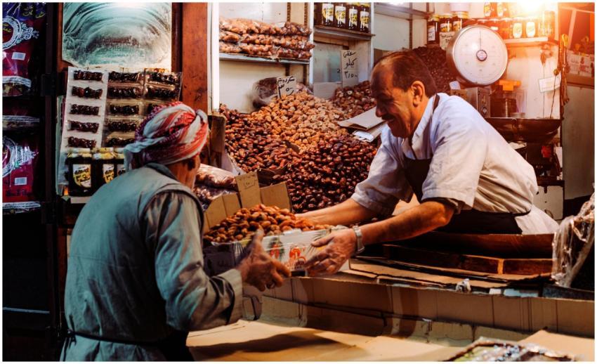 Two men exchanging dates in a vibrant Dubai spice