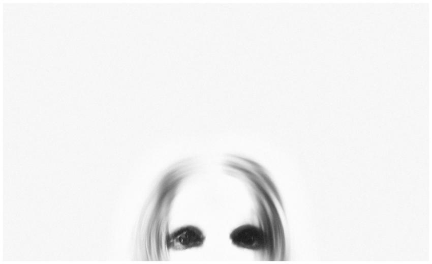 A ghostly figure with black eyes emerges from a bl