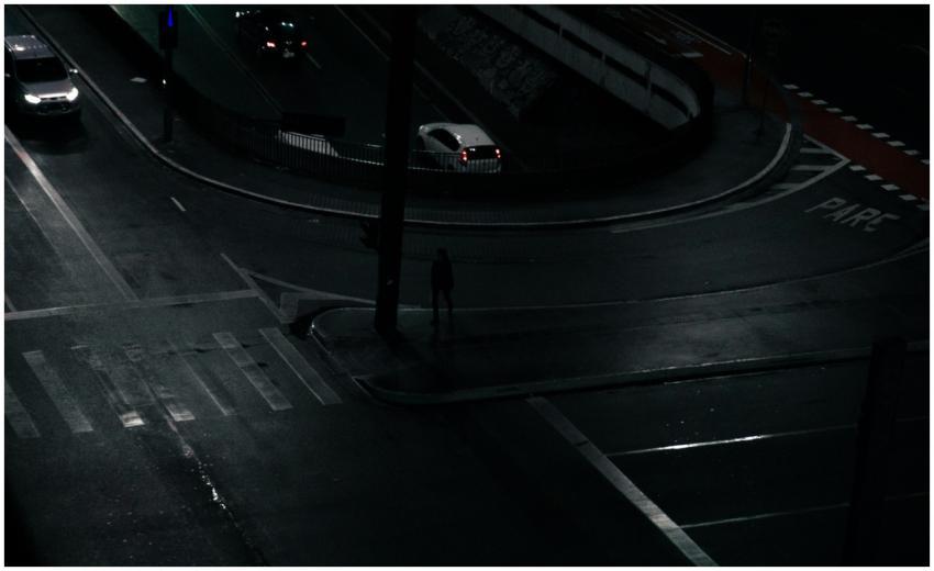Nighttime urban intersection with cars and dim str