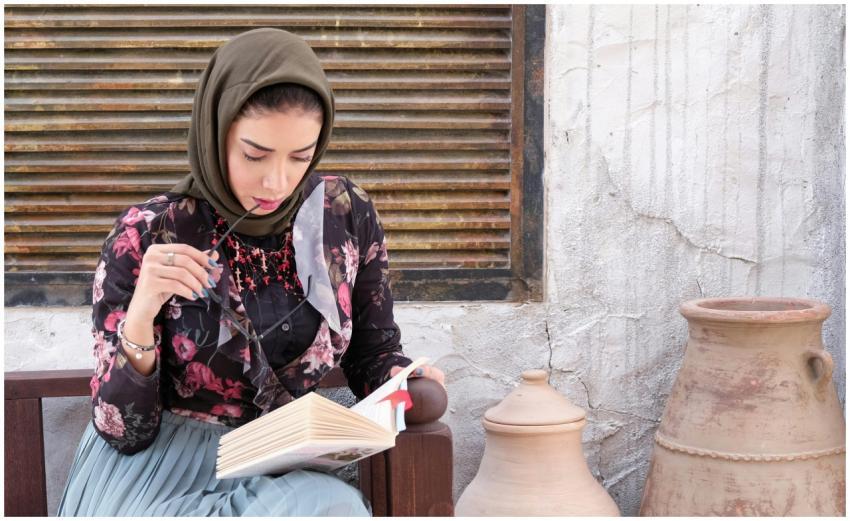 A woman in traditional wear reading a book outdoor