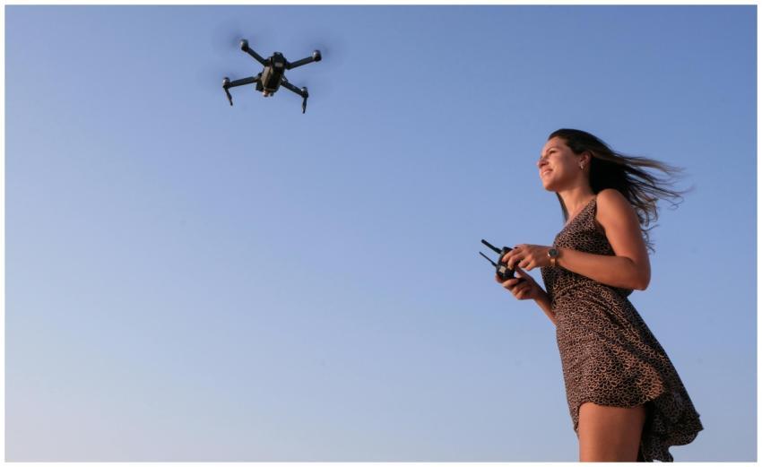 A woman enjoying flying a drone outdoors under a c