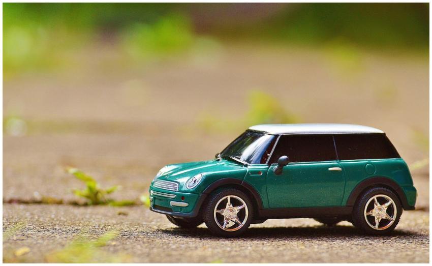 Green toy Mini Cooper car on pavement featuring a