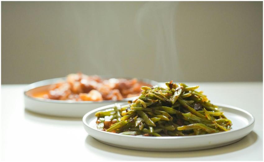 Close-up of a steaming green bean dish with anothe