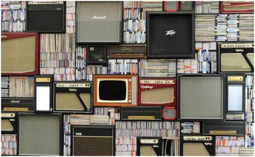 A wall of vintage speakers and TVs surrounded by b