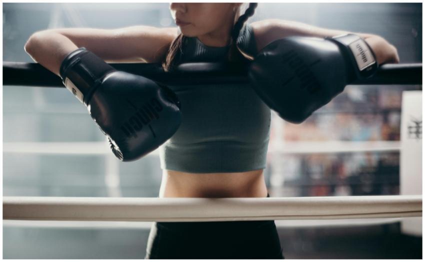 Young female boxer resting on the ropes in a boxin