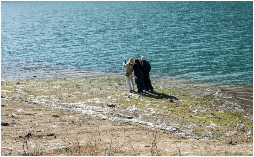 Three people taking a selfie by a lake, enjoying a