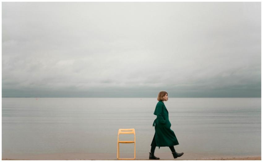 A solitary woman walks by the ocean, capturing cal