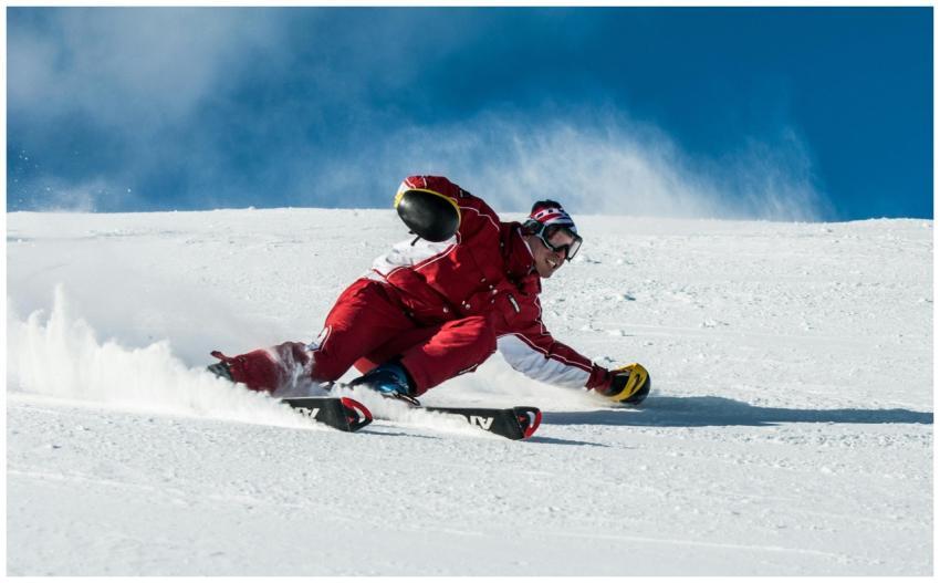 A skier in vibrant red gear skillfully navigates a