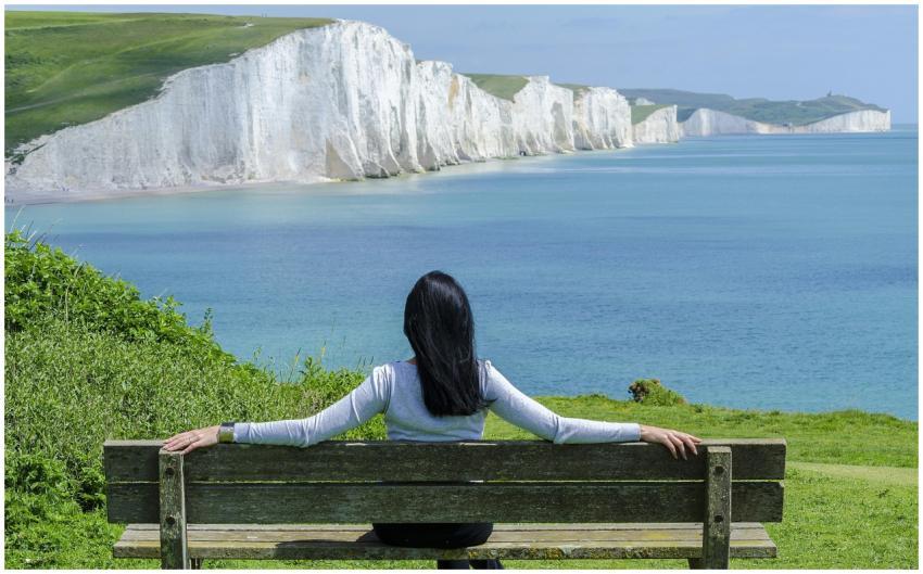 A woman relaxes on a bench, admiring the scenic cl