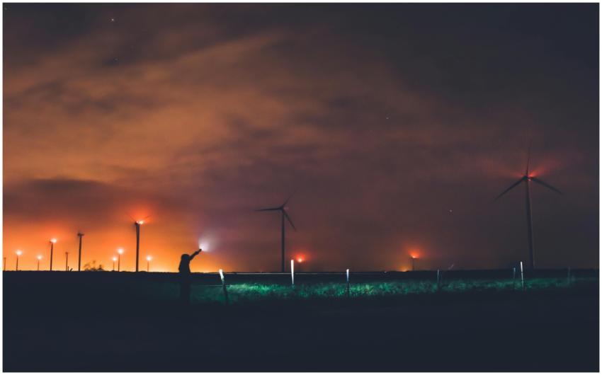 Silhouette of a person near wind turbines at night