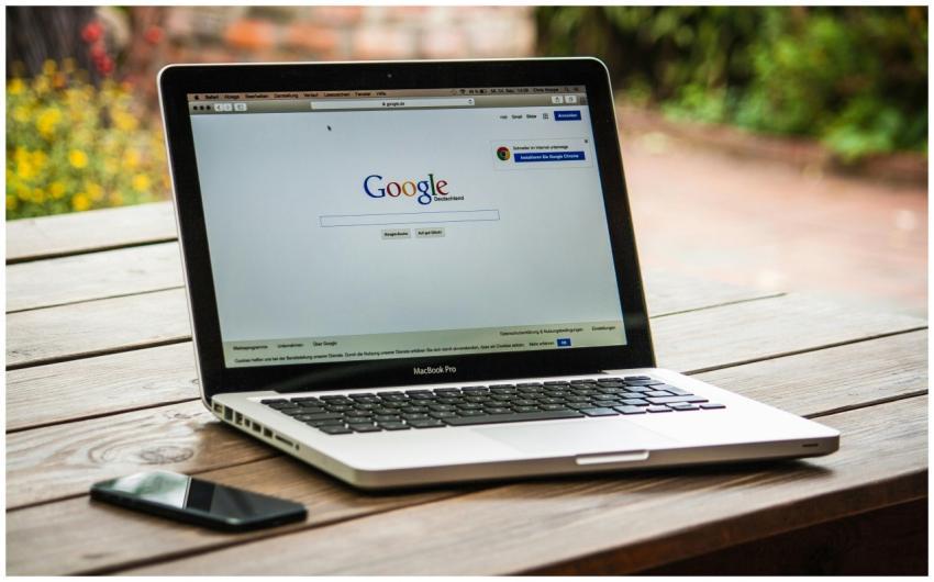 A MacBook Pro displaying Google Search on a wooden