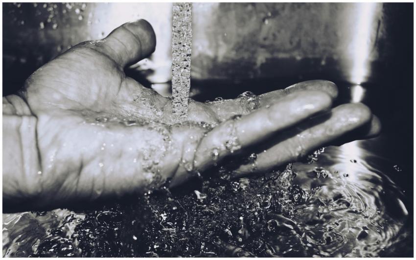 Black and white image of water flowing into a hand