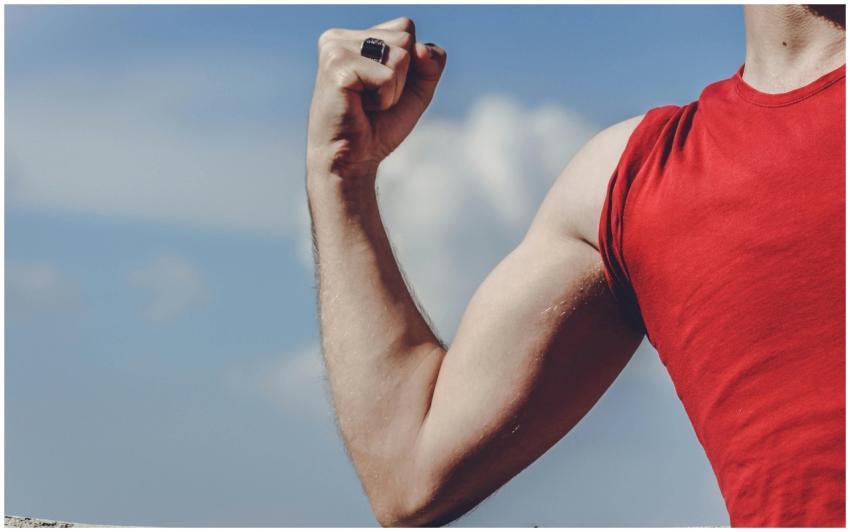 Close-up of a flexed arm in a red shirt against a