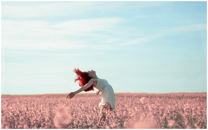 Woman with red hair in a white dress expressing fr