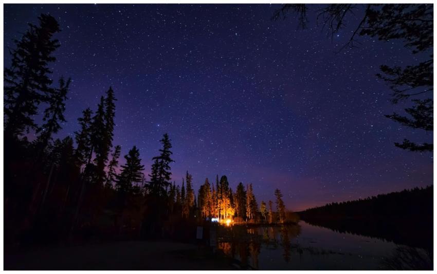 A serene night scene with starry sky, glowing camp