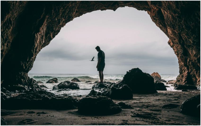 Silhouette of a person standing in a sea cave at M