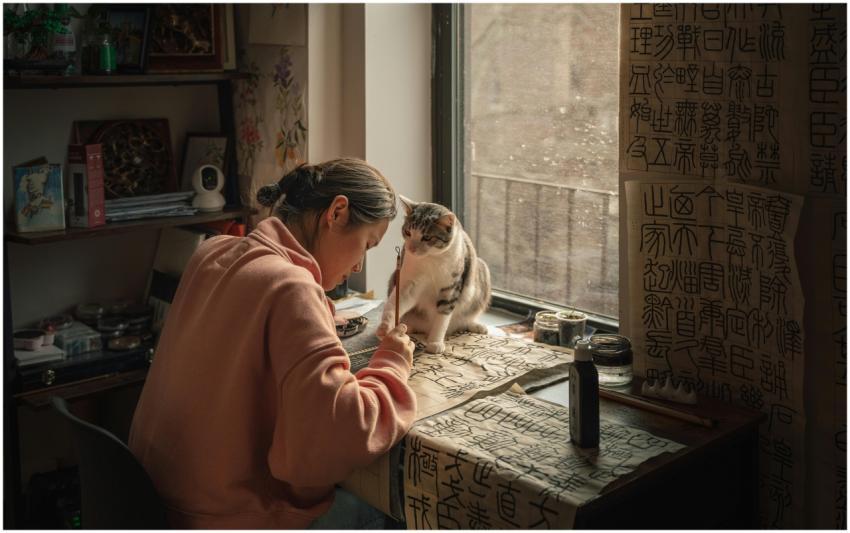 A woman practices Chinese calligraphy beside a cur