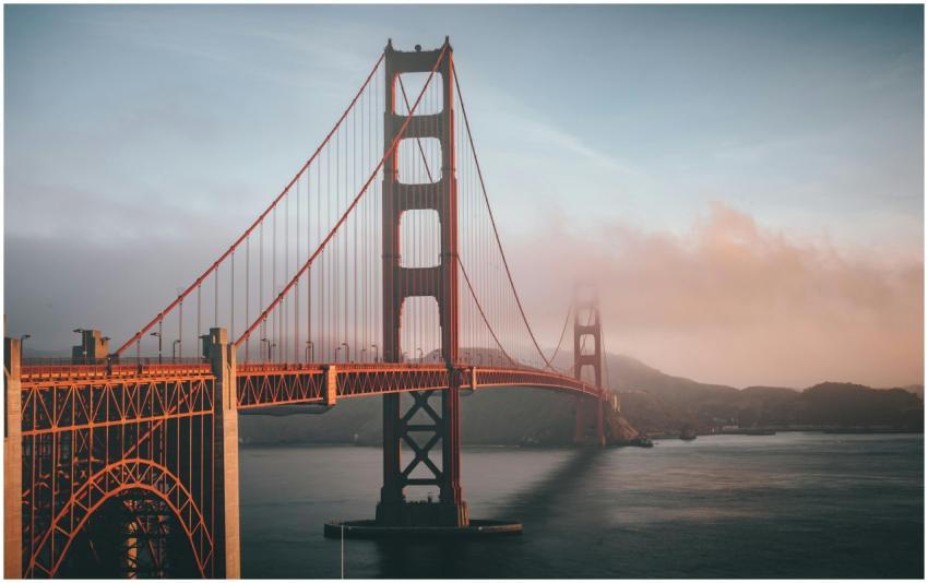 Golden Gate Bridge shrouded in fog during sunset,