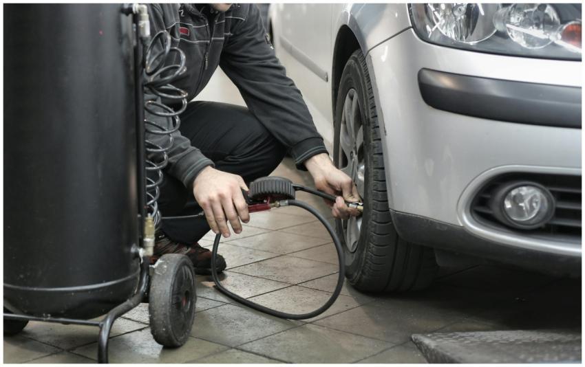 Mechanic inspecting and adjusting tire pressure in