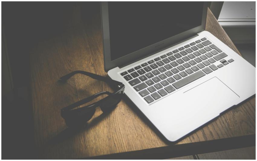 A stylish wooden desk featuring a sleek laptop and