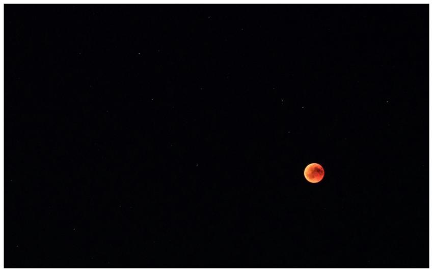 Blood moon eclipse visible over a starry sky in Mö