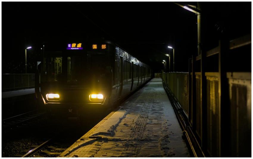 Train passing through a snowy station at night