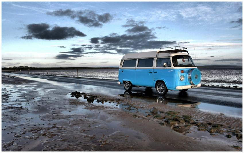 Vintage blue campervan on a coastal road beside th