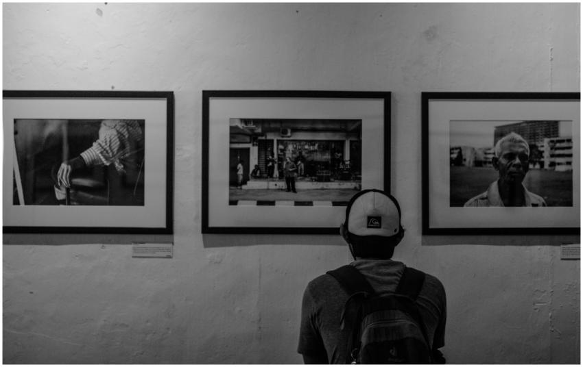 A man in a cap and backpack admires monochrome art
