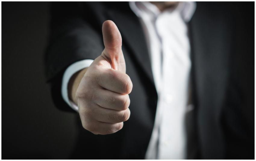 A close-up of a man's thumbs up gesture, symbolizi