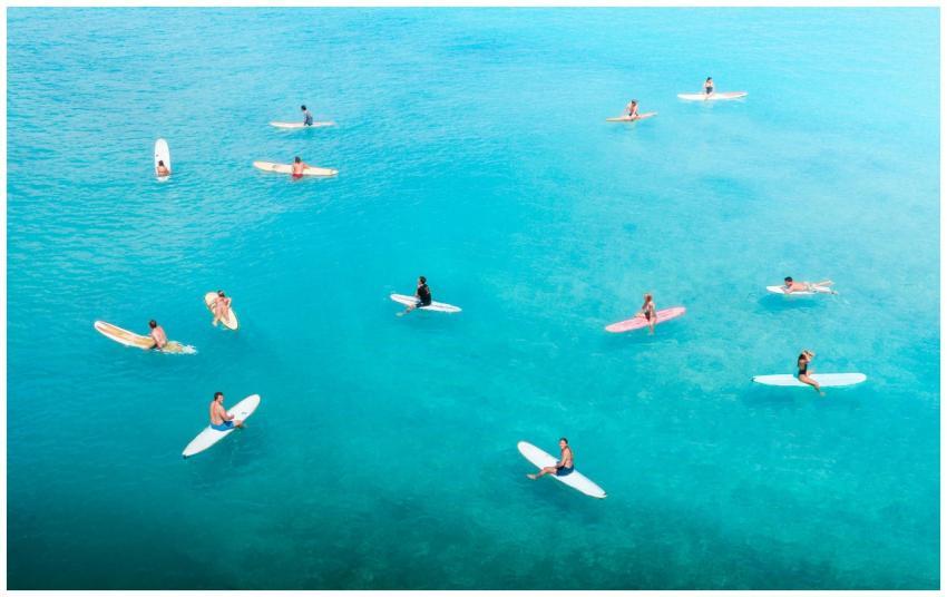 Aerial shot capturing surfers in clear turquoise w