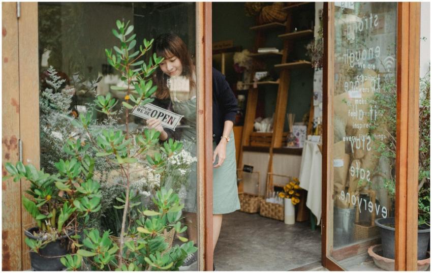 Positive young Asian female florist in apron stand