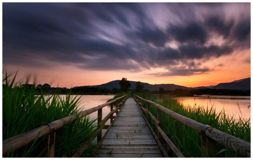 A tranquil scene of a wooden pier at sunset with d