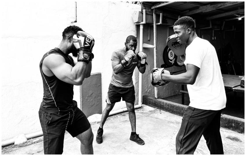 Three men engaged in a focused boxing training ses