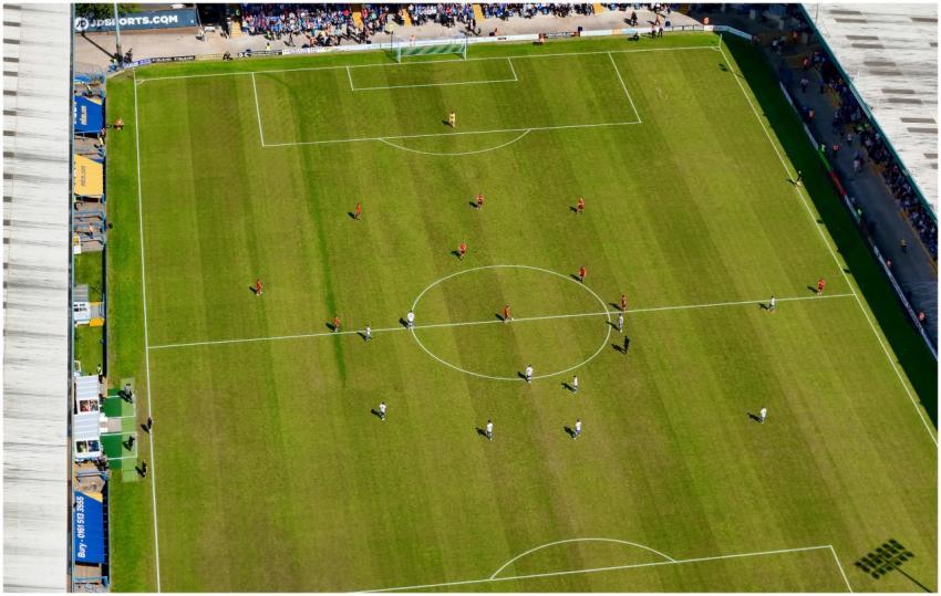 Aerial view of a football match in a sunlit stadiu