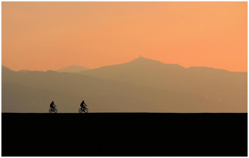 Cyclists on a road at dusk with mountains silhouet