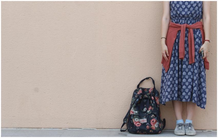 Stylish woman in a patterned dress and sneakers st